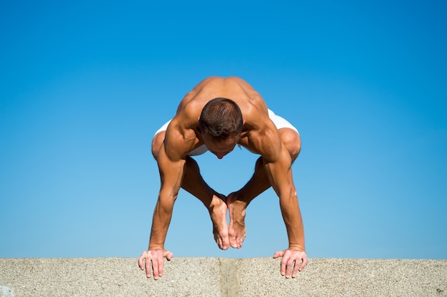 Muscular man balance yoga position. Yoga instructor with muscular body stretching. Sport and health care. Coach demonstrate yoga asana outdoors. Flexible body is his merit. Mental and physical health.