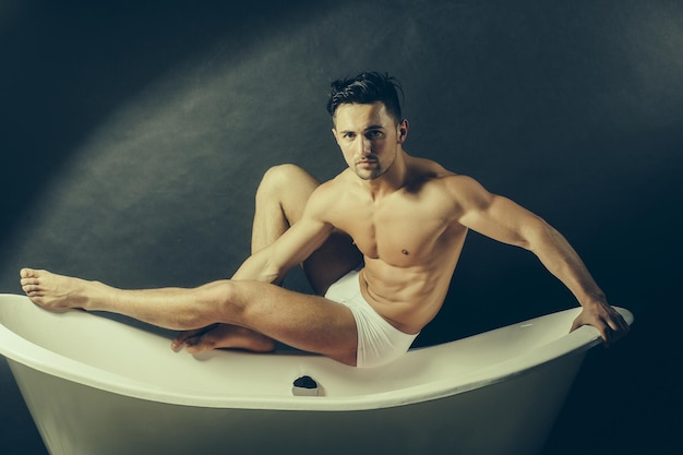 Muscular man on bathtub