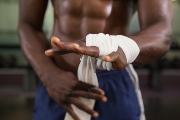 Muscular man binds bandage on his hand