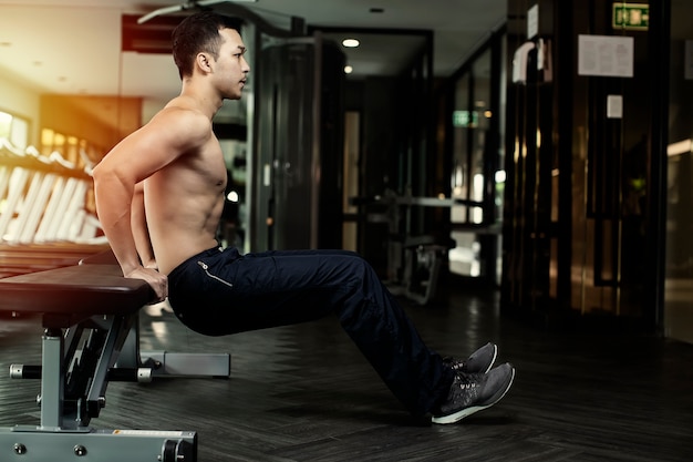 muscular man doing push-up on chair  