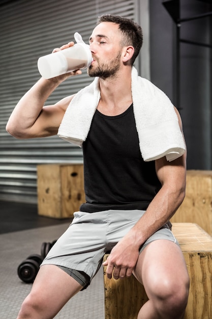 Muscular man drinking protein shake at the crossfit gym