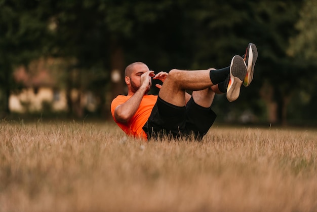 Muscular man exercising doing sit up exercise Athlete with six pack white male Outdoor training Sports and healthy lifestyle Bearded blackhaired guy doing crunches Outdoors