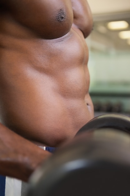 Photo muscular man exercising with dumbbell in gym