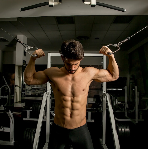 Muscular man in gym doing exercises for biceps