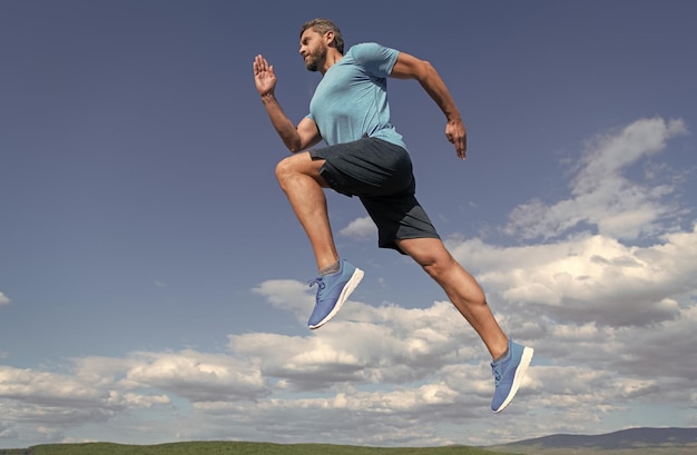 Muscular man running in sportswear outdoor on sky background challenge