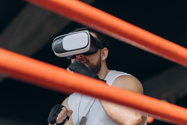 Muscular man in VR goggles and boxing gloves throwing punches towards camera