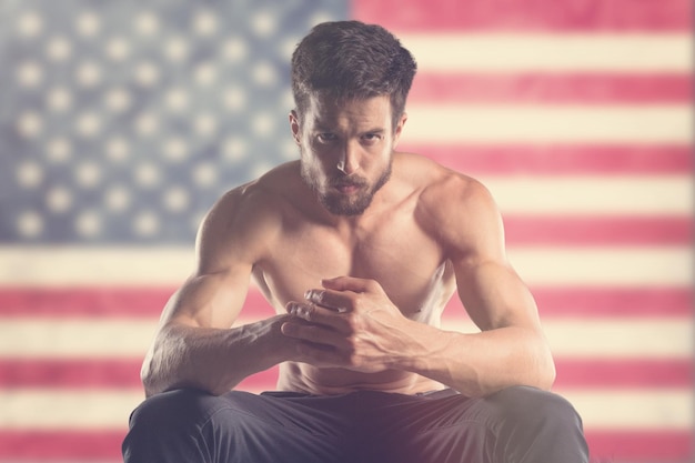 Photo muscular man with us flag behind