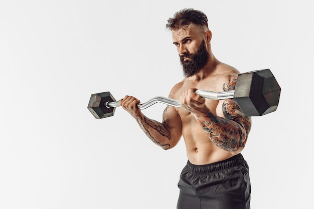 Muscular man working out in studio doing exercises with barbell at biceps strong male naked torso abs Isolated on white background