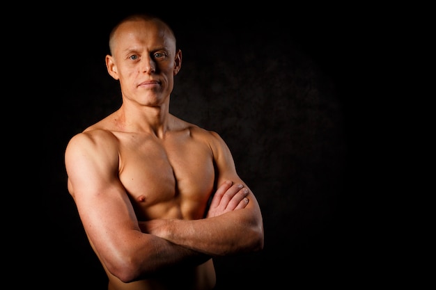 Muscular model sports young man on dark background. Fashion portrait of strong brutal guy