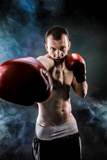 Muscular muay thai fighter punching in smoke