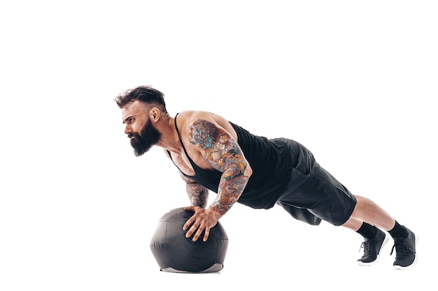 Muscular tattooed bearded male exercising