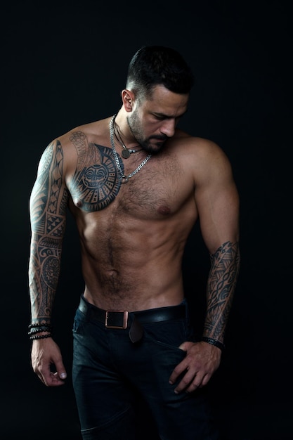 Muscular torso Jewelry for real men Bearded man with tattooed torso Macho sexy bare torso Fit model with tattoo art skin Sportsman or athlete with beard and hair Sport and fitness Masculinity