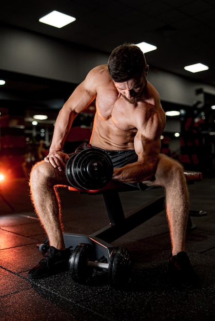 Muscular young man training in gym Athletic shirtless bodybuilder