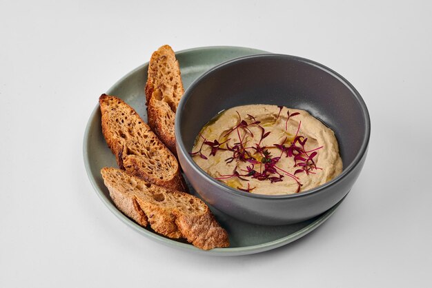 Mushroom mousse with truffle oil in a bowl with a baguette on a gray background