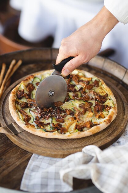 Mushroom pizza on a wooden board. Serving pizza. The chef cuts the pizza.