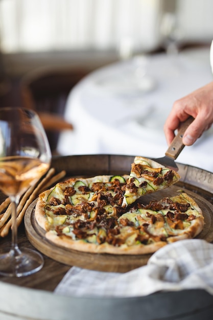 Mushroom pizza on a wooden board. Serving pizza. The chef cuts the pizza.