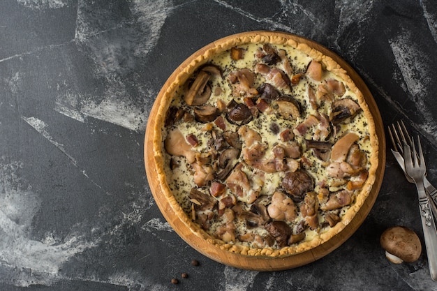 Mushroom Quiche Pie with champignons and cheese on dark background