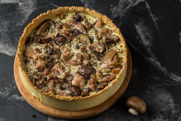 Mushroom Quiche Pie with champignons and cheese on dark background