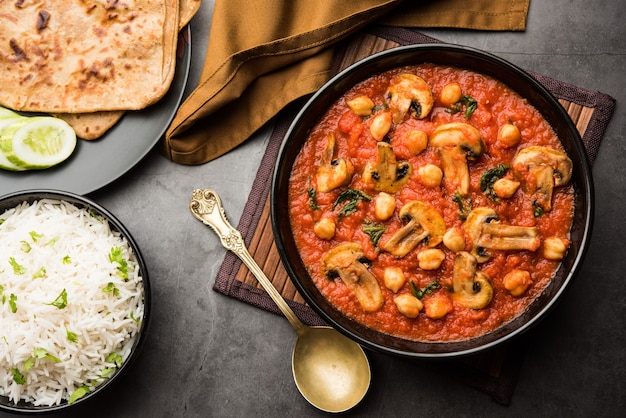 Mushroom sabzi in tomato curry with chickpea and spinach, Indian main course menu served with Paratha and cooked white rice