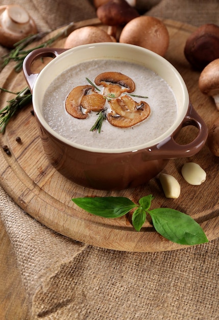 Mushroom soup in pot on napkin on wooden background