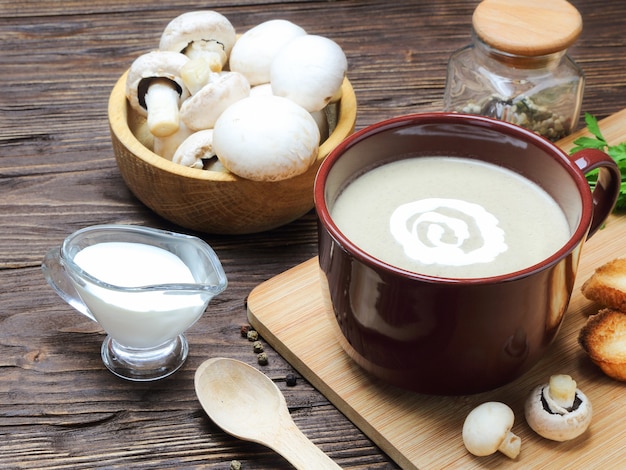 Mushroom soup puree of champignon in a brown cup on a wooden table