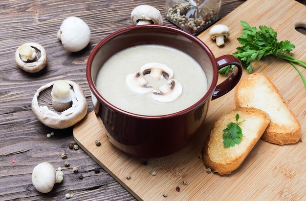 Mushroom soup puree of champignon in a brown cup on a wooden table