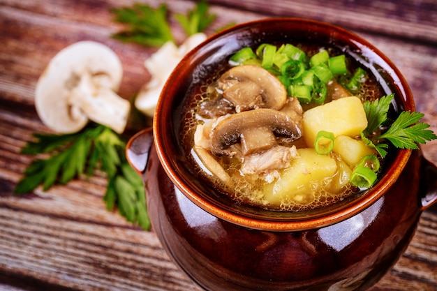 Mushroom soup with potatoes and chives in a clay pot