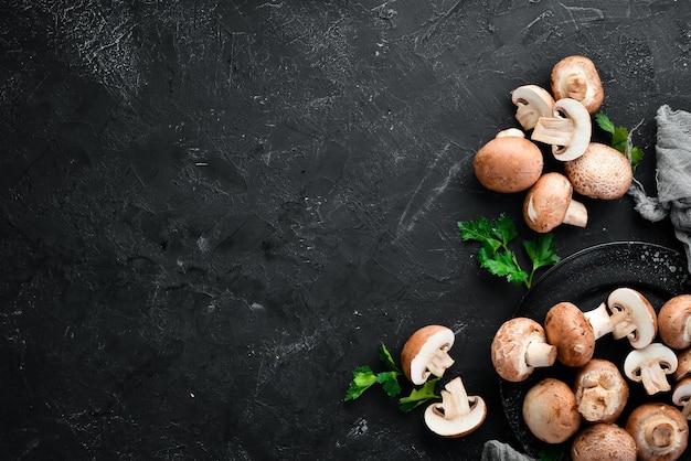 Mushrooms on a black stone background Champignons Top view Free copy space