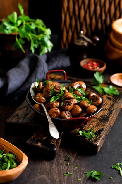 Mushrooms champignon fried in soy sauce with pepper and steamed onions in an old metal bowl on an old vintage table Selective focus