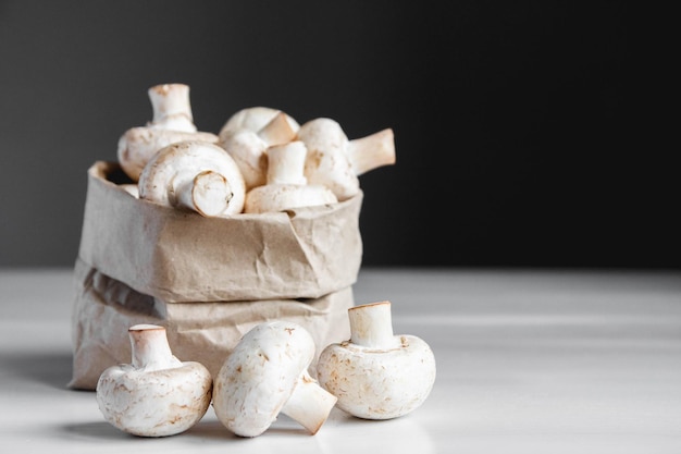 Mushrooms champignons in paper bag on a white wooden table