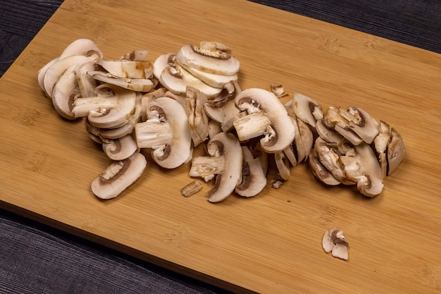 Mushrooms on a cutting board during cleaning and cutting as part of the process of preparing fresh champignons for subsequent freezing