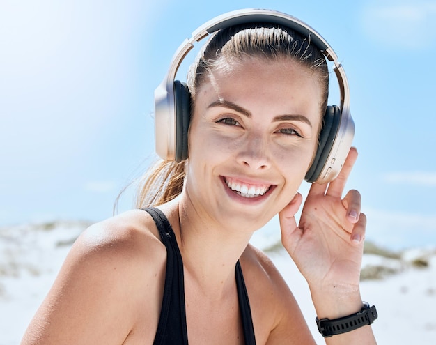 Music fitness and woman at the beach for exercise wellness and cardio training while listening to radio Podcast workout and portrait of girl relax smile and enjoy motivation audio track for run