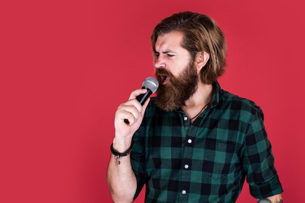 Music is the universal language of mankind bearded man in checkered shirt sing song casual guy express human emotions while singing emotional hipster with mic male singer with microphone karaoke