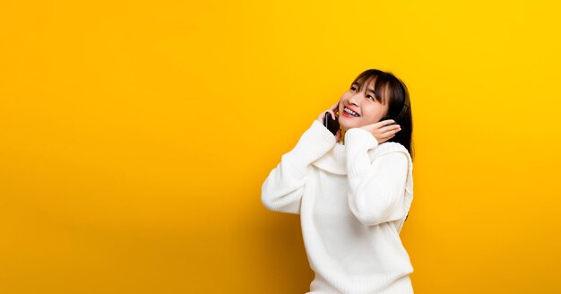 Music listening to music Beautiful Asian woman in headphones listening to music and enjoying the sound of music on a yellow background