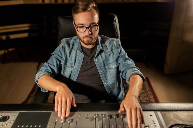 Photo music, technology, people and equipment concept - man at mixing console in sound recording studio