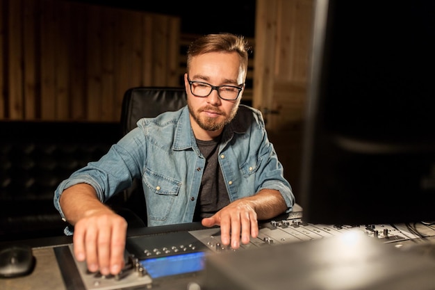 Photo music, technology, people and equipment concept - man at mixing console in sound recording studio