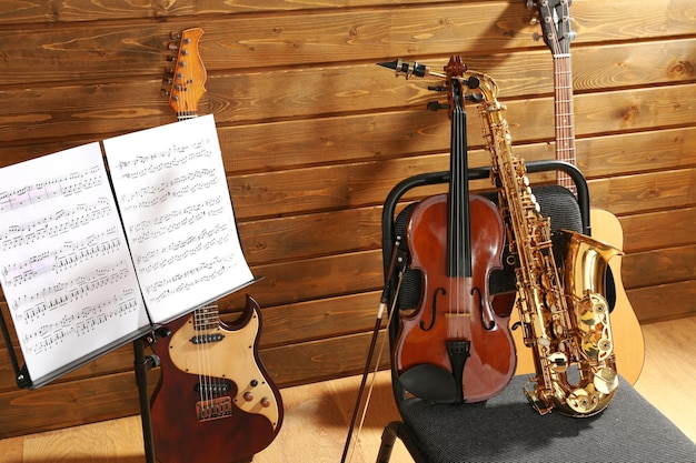 Musical instruments on a chair and note holder against wooden background