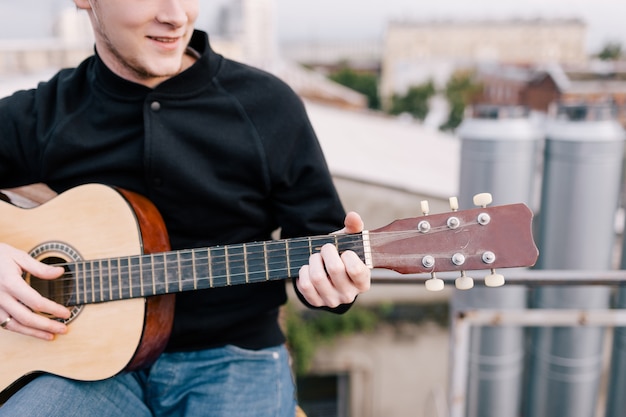 Musician at party celebration on roof. Unrecognizable happy guitarist outdoors