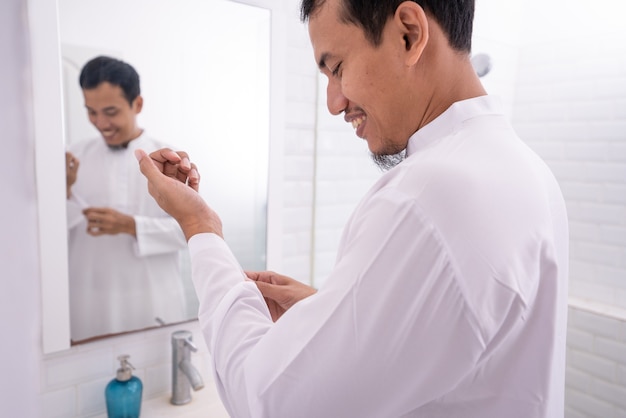 Muslim asian man looking at mirror and get dressed before going to the mosque