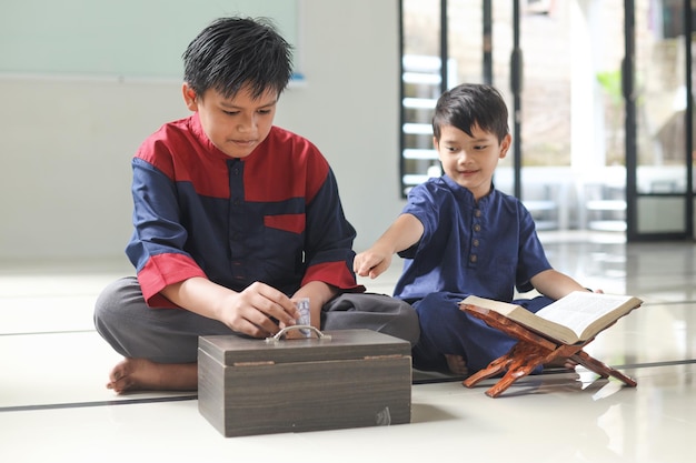 Muslim boy put money into the donation box inside the mosque help each other concept