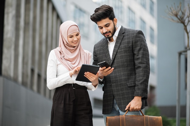 Muslim business colleagues using modern gadgets outdoors