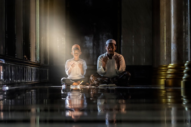 Muslim children kid and old man teaching wearing white shirts Doing prayer reading book