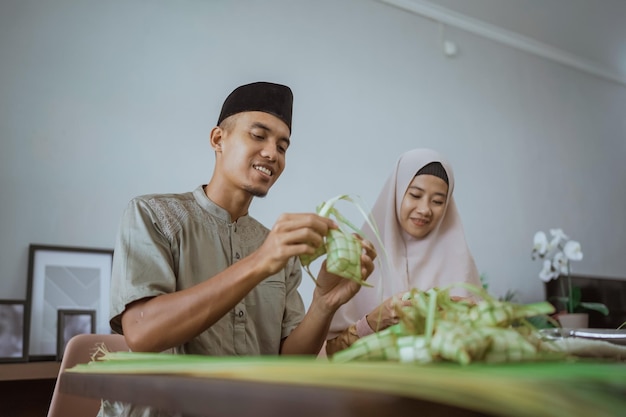 Muslim couple asian making ketupat rice cake at home using palm leaf