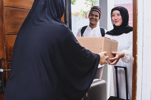 Muslim couple coming back home and giving box of souvenirs to mother in Eid Mubarak moment.