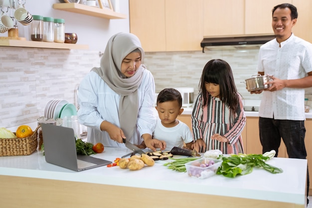 Muslim family with two children cooking together at home preparing for dinner and iftar break fasting