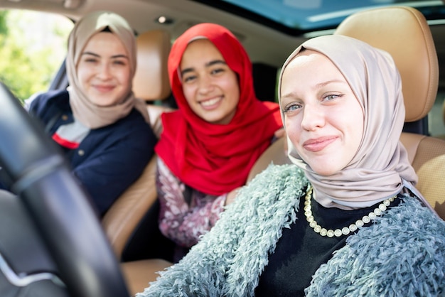 Muslim female friends enjoying road trip traveling at vacation in the car. High quality photo