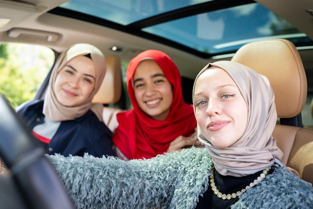 Muslim female friends enjoying road trip traveling at vacation in the car. High quality photo