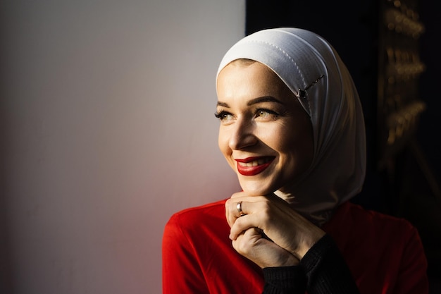 Muslim girl is smiling at home. Close-up portrait of muslim model weared in traditional islamic scarf. Islam religion.