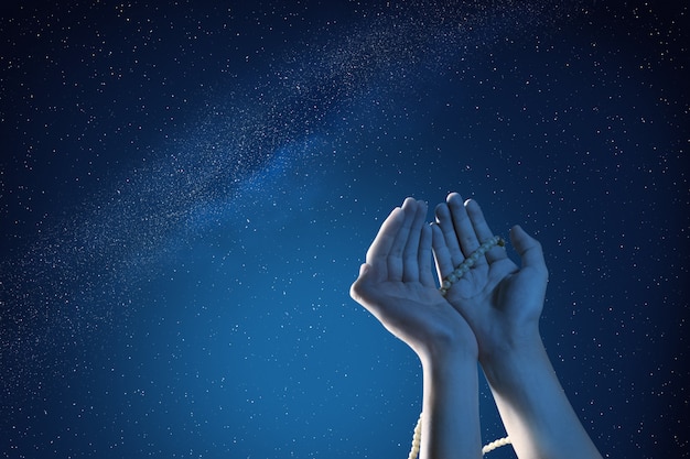 Muslim hands praying with prayer beads at outdoor 