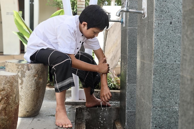 Muslim kids washing left hand to elbow arms, ablution procedure before praying salah.